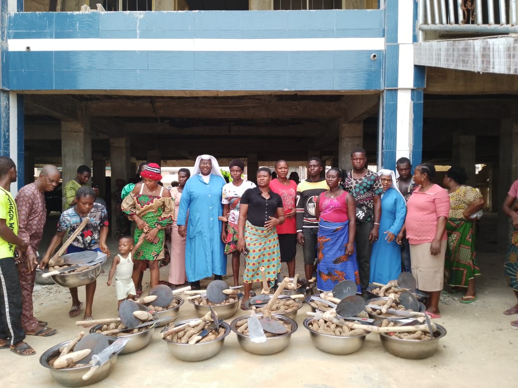 A group of women standing behind handmade clay pots outdoors.