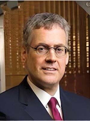 Professional portrait of a middle-aged man in glasses and a suit.