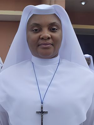 A smiling nun dressed in a white habit and veil.