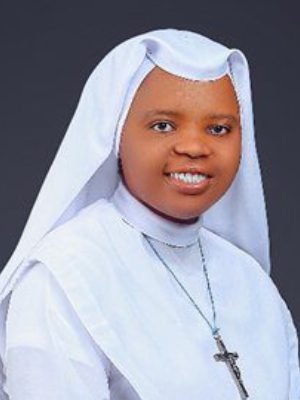 Portrait of a smiling nun in a white habit and veil.