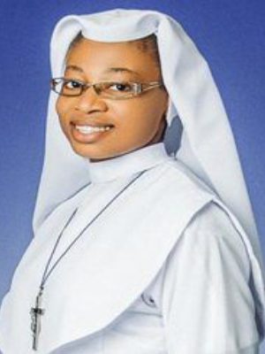 Portrait of a smiling nun wearing glasses and a white habit.