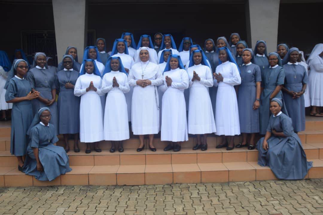 Group of nuns and women posing together on steps.