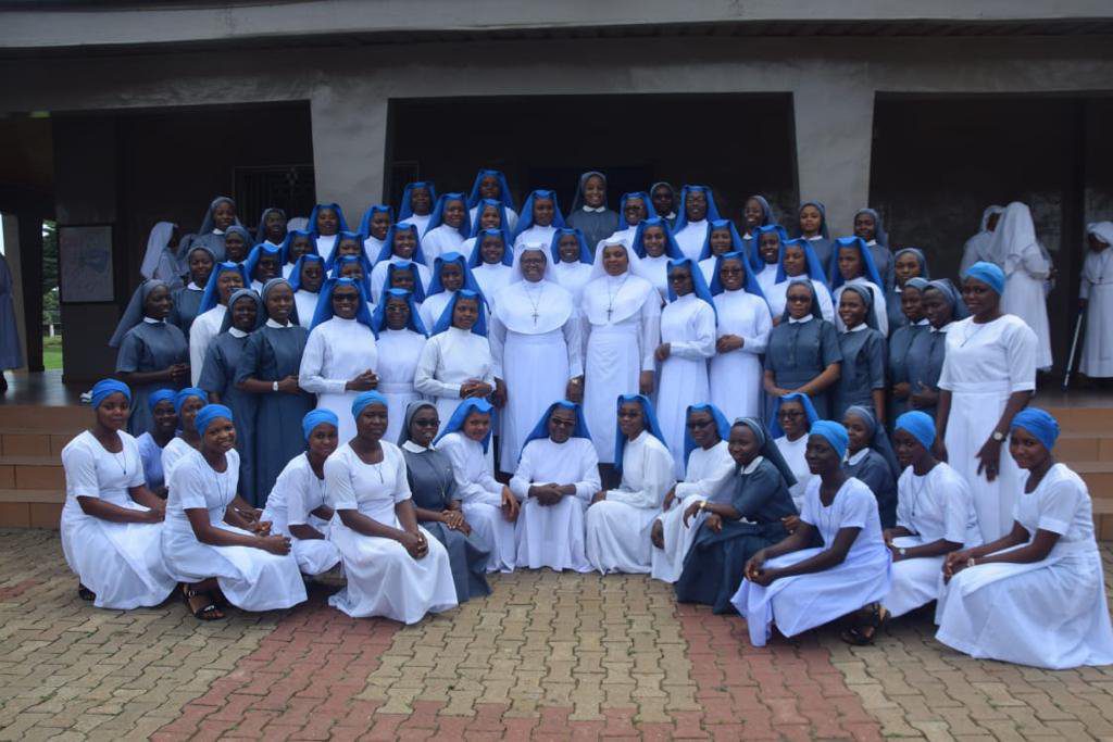 Group photo of nursing staff and trainees in uniform outside a building.