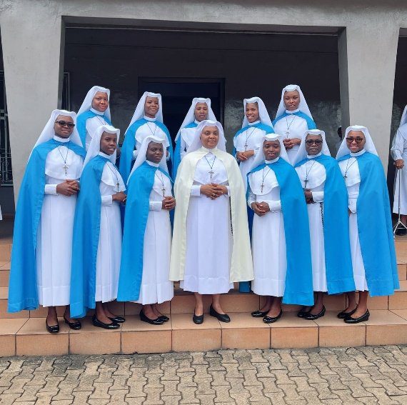 A group of nuns in blue and white habits posing together outside.