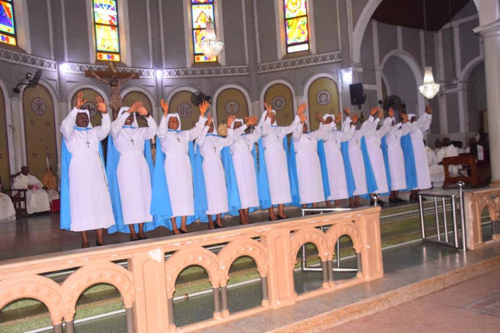 Choir of women in blue dresses singing in a church.
