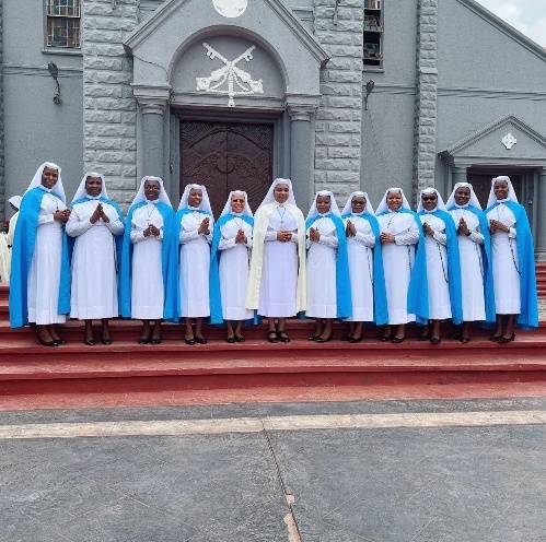 A group of women in blue and white robes standing in front of a church.