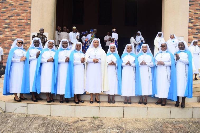 Group of nuns in white and blue habits posing on steps.