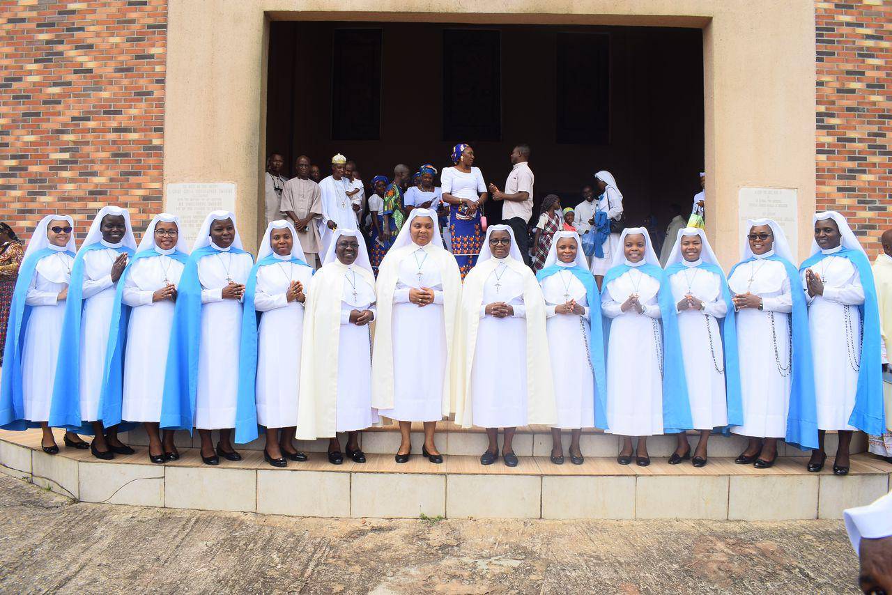 A group of people in traditional attire standing on steps outside a building.