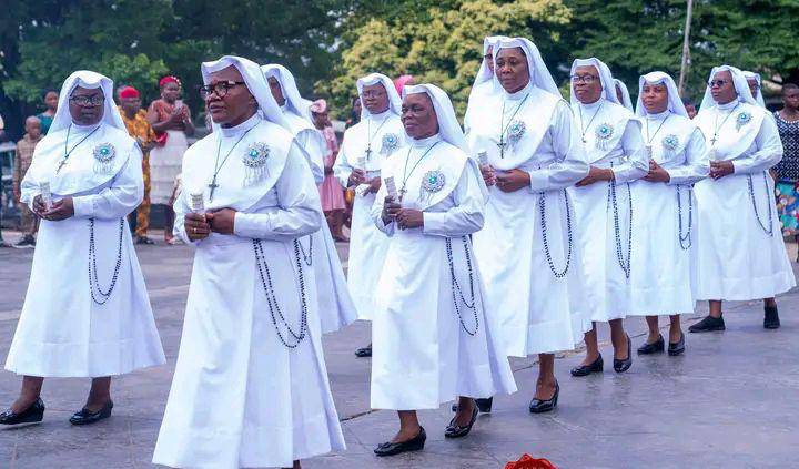 A group of nuns walking outdoors in white habits.