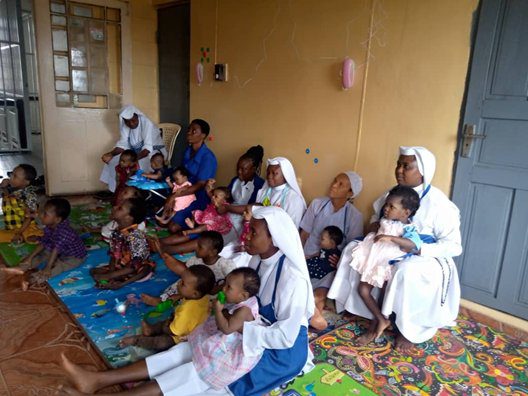 Nuns and children gathered in a modest room, engaging in activities.