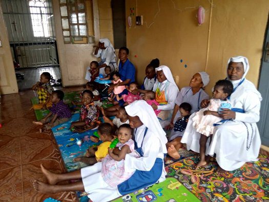Nuns and children gathered in a room for a community activity.