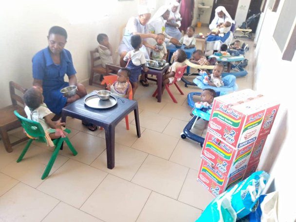 People sitting and eating in a casual indoor setting with packaged goods nearby.