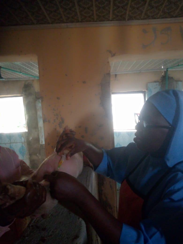 A nun handing an item to a woman inside a room with windows.
