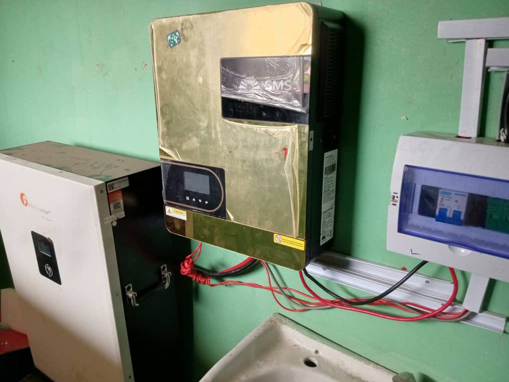 Old electrical control panel mounted on a green wall with wires connected.