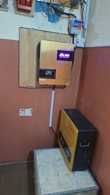 Inverter and solar battery setup in a room with brown walls.