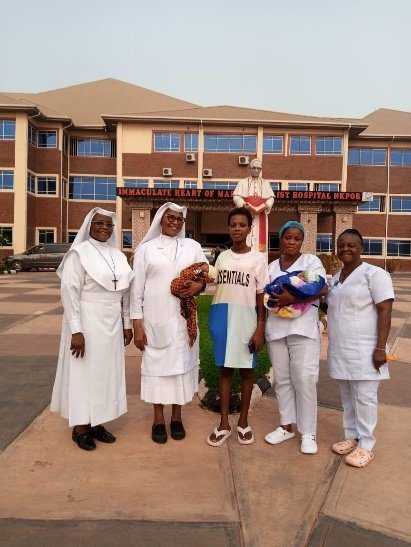 A group of women, including nuns and nurses, posing outside a school building.