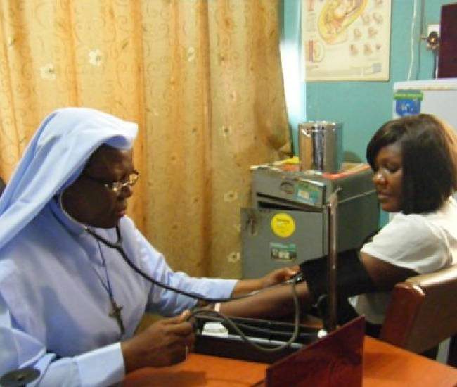 A healthcare worker checks a patient's blood pressure in a clinic.