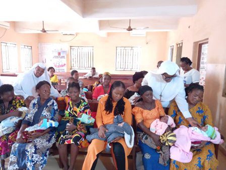 Nurses attending to mothers and babies in a bright clinic room.