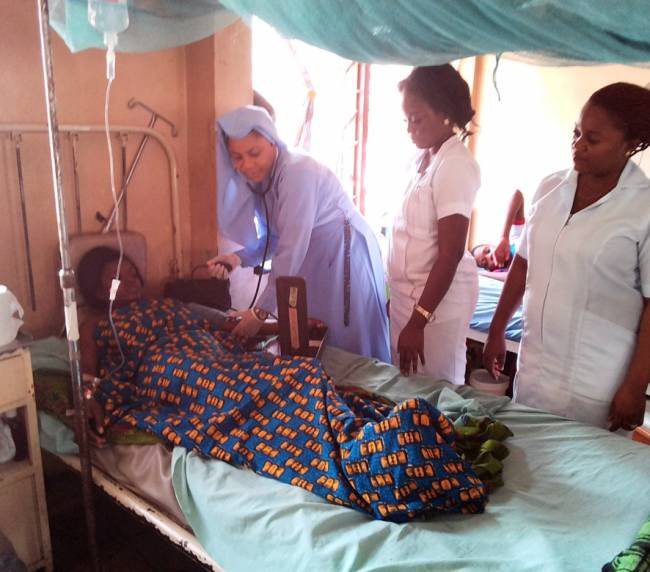 Healthcare workers attending to a patient in a hospital bed.
