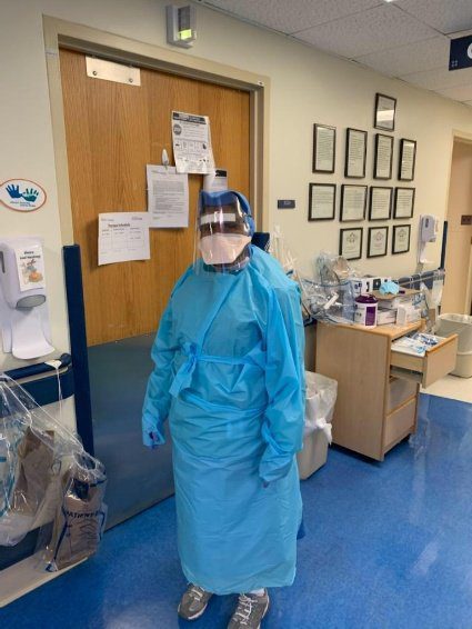 Healthcare worker in full protective gear inside a medical facility.