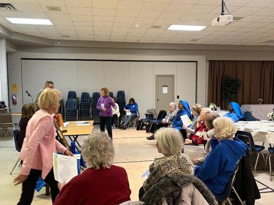 A group of elderly people gathered in a community room for an event.