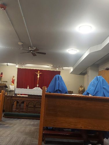 Two people in blue veils seated in a church pew during a service.