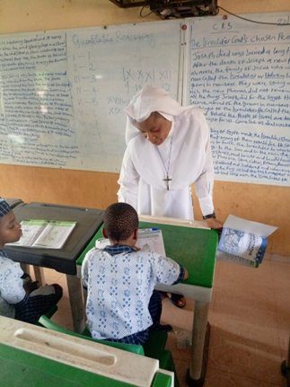 Teacher assisting two young students in a classroom.