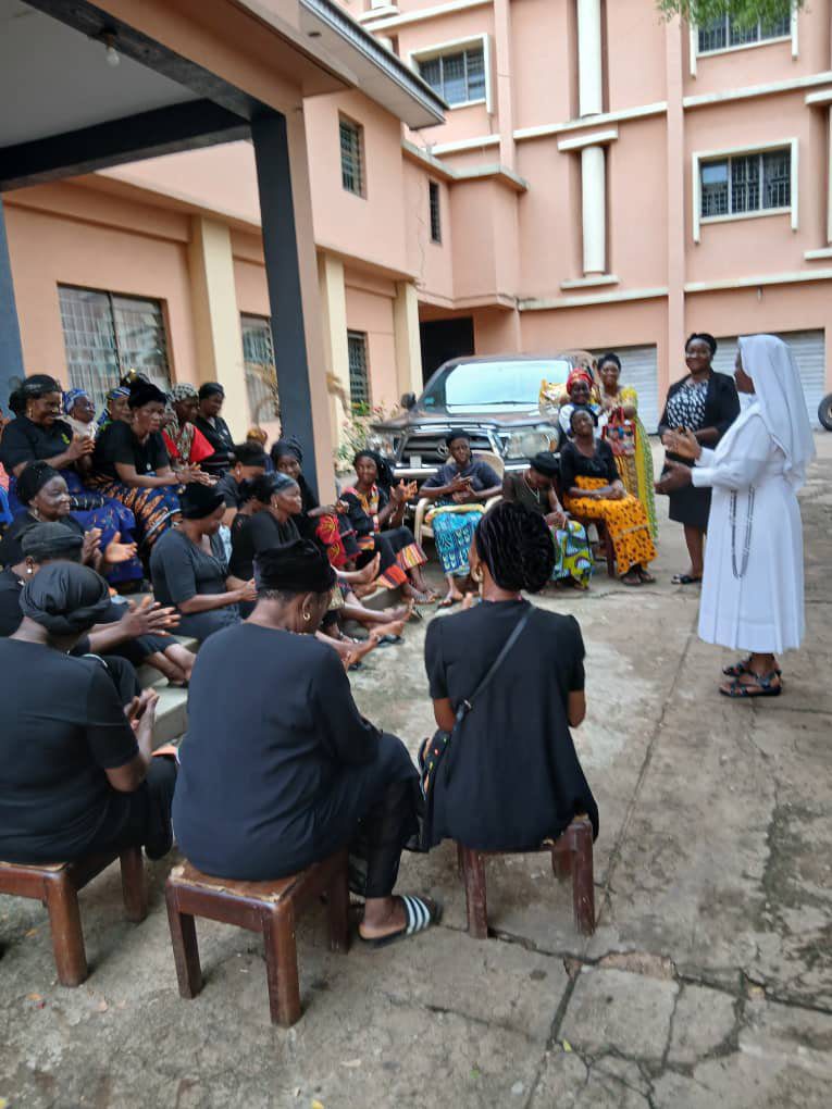 A group of people gathered outdoors listening to a speaker in religious attire.