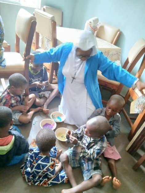 A caregiver shares a meal with children around a table.