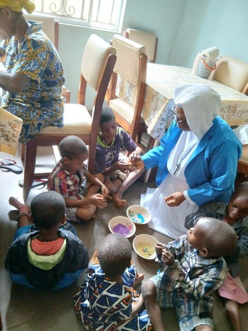 A woman serving food to children seated on the floor.