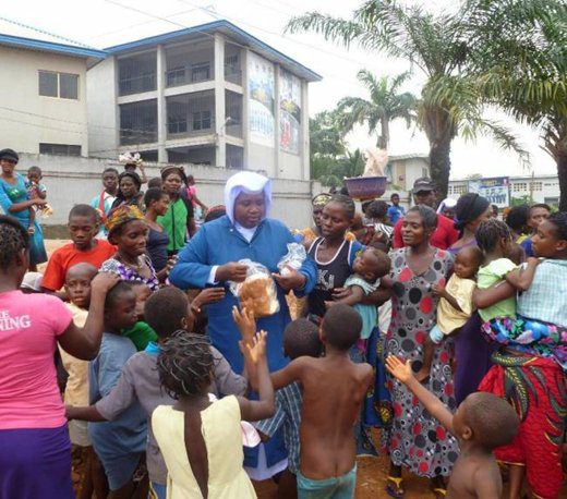 A nun handing out food to children in a community gathering.