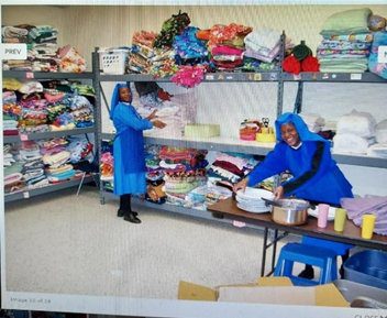 Two women in blue uniforms organizing colorful fabric in a workshop.