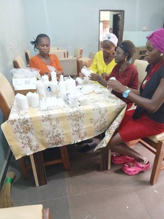 Four women sitting around a table crafting with white materials.