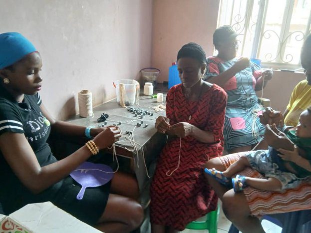 Four women engaged in knitting together indoors during the day.