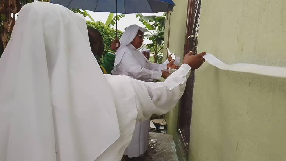 Nuns preparing and decorating an outdoor area with white cloth and an umbrella.