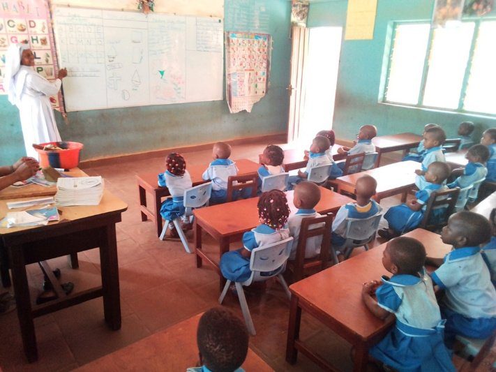 Young students in blue uniforms attentively seated in a classroom.