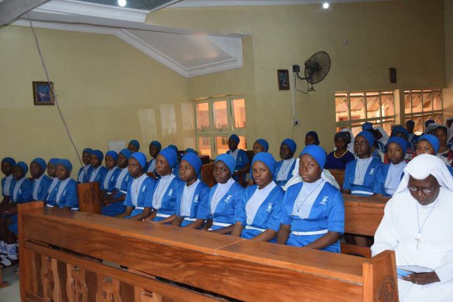 Group of women in blue uniforms seated in a room.