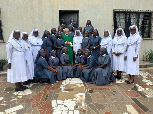 A group of nuns posing outside a building.