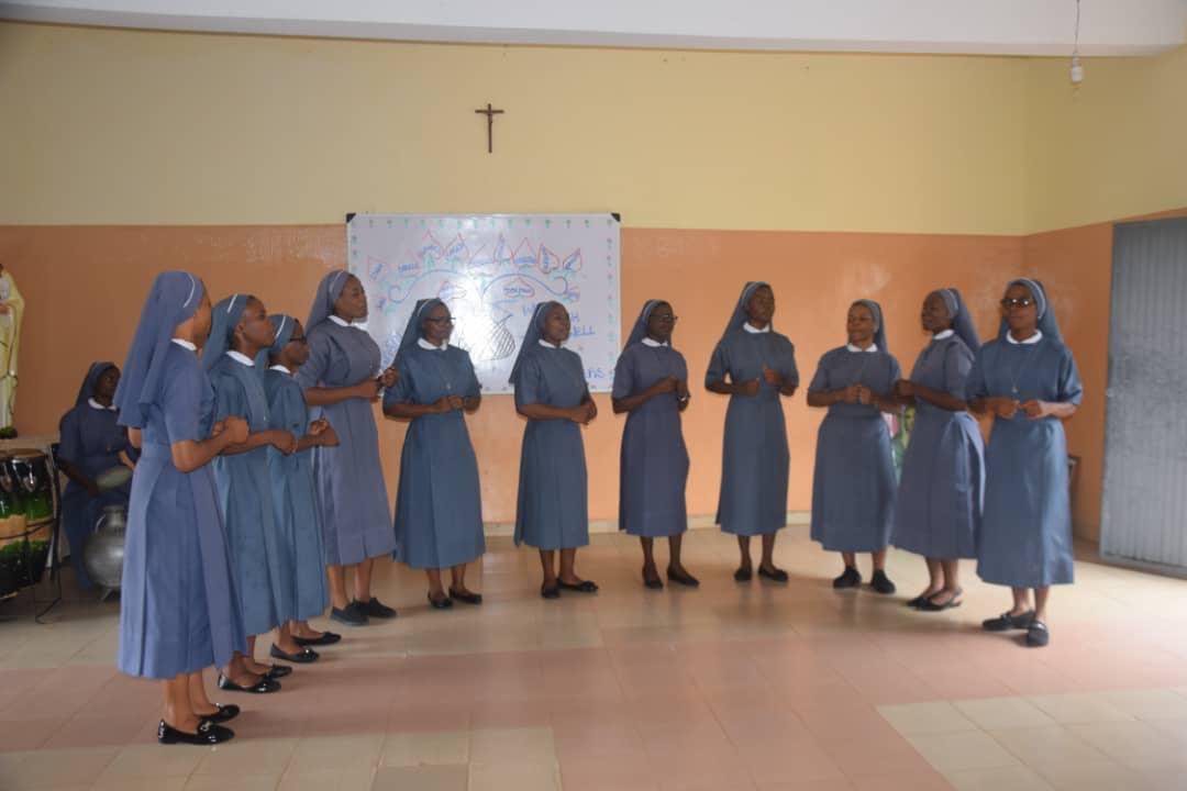 A group of nuns standing in a circle inside a room.