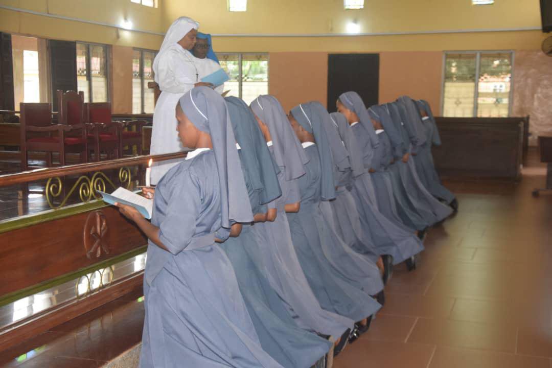 Nuns kneeling in prayer inside a church.